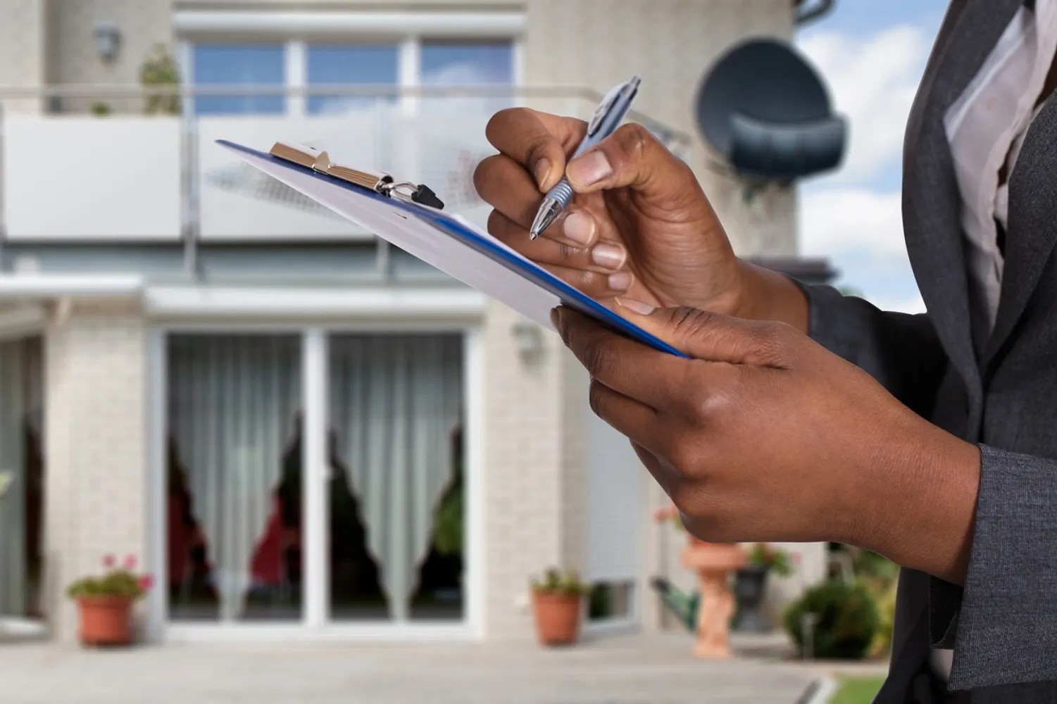 african american woman standing in front of an apartment building, holding a checklist